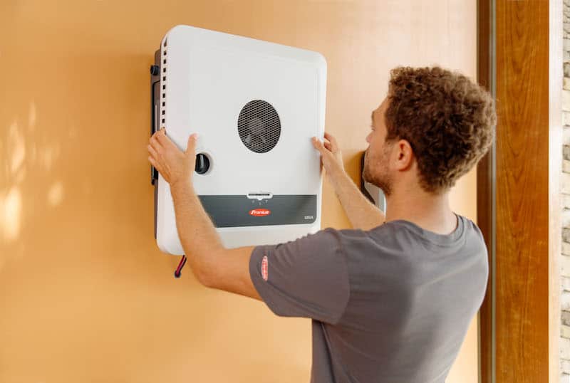 Image of a young guy installing a Fronius inverter